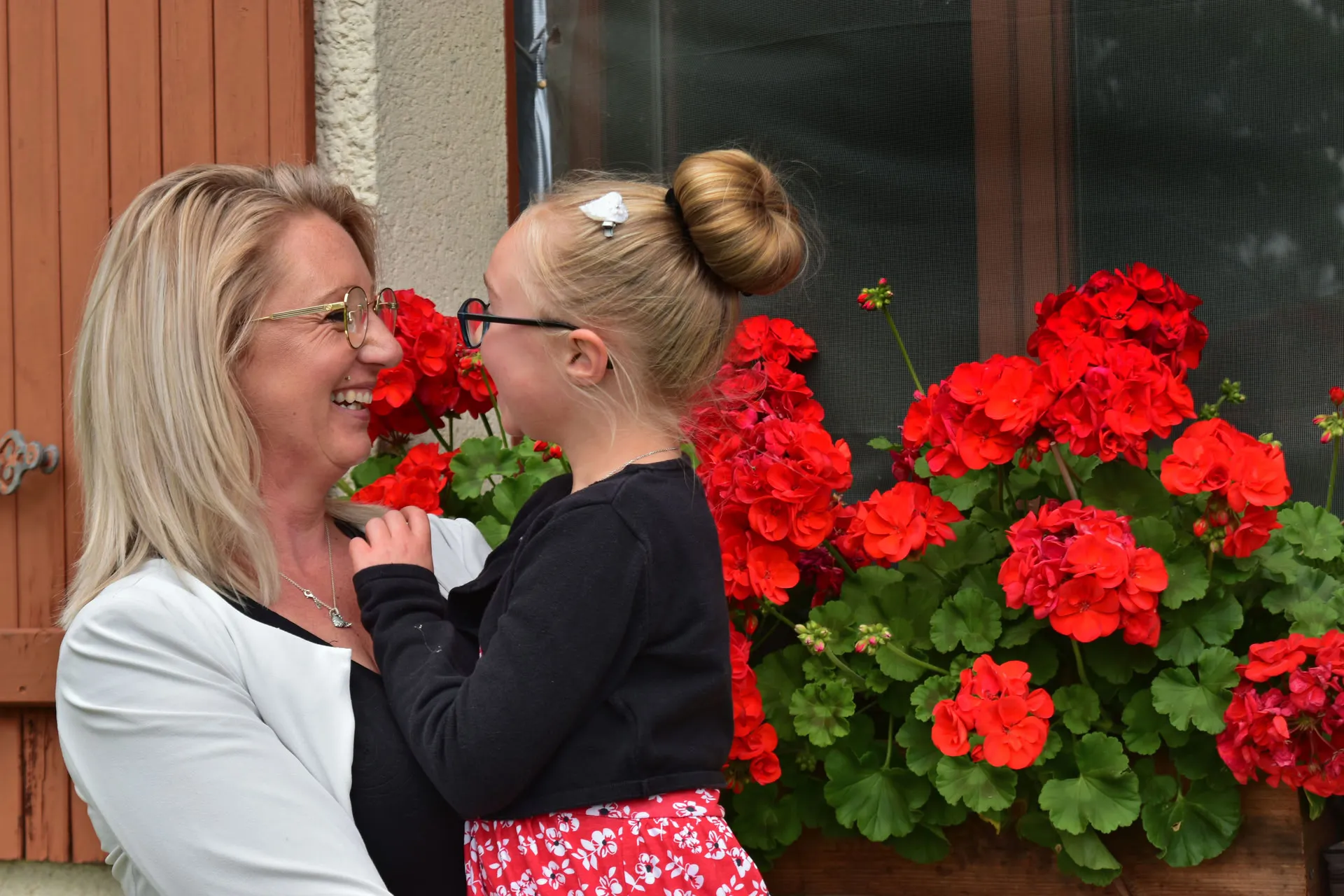 Famille, maman avec sa fille dans les bras, se regarde en souriant, arrière plan floral